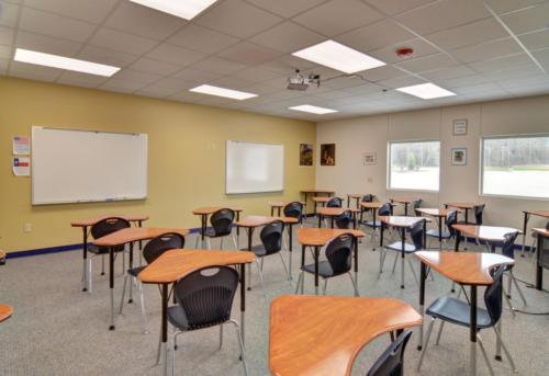 A classroom with triangular desks facing toward a yellow wall