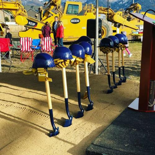 Shovels sticking out of the dirt with hard hats sitting atop