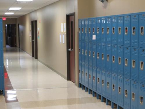 A bank of blue lockers lines a school hallway