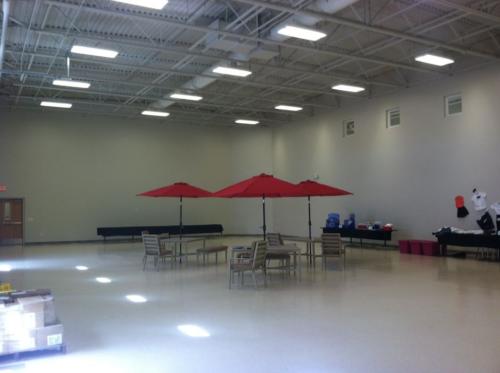 Outdoor tables with red umbrellas set up in a large room