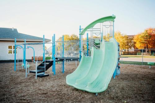 Blue and green playground equipment behind the school