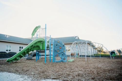 Blue and green playground equipment behind the school